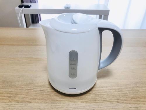 a white electric kettle sitting on a table at 桜並木と航空公園の近くにある閑静なお部屋 最大5名 t10 in Tokorozawa