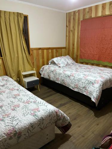 een slaapkamer met twee bedden en een stoel erin bij Casa nueva en recinto privado in Licán Ray