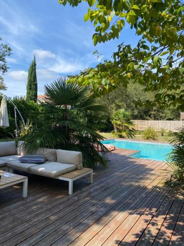 - un canapé installé sur une terrasse en bois à côté de la piscine dans l'établissement Villa avec piscine, à Martignas-sur-Jalle