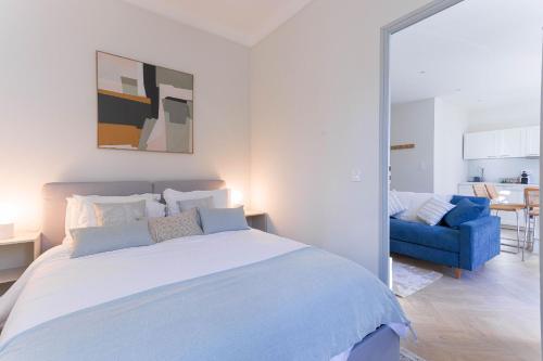 une chambre avec un grand lit et un canapé bleu dans l'établissement Leandre Sardou by Halldis, à Cannes