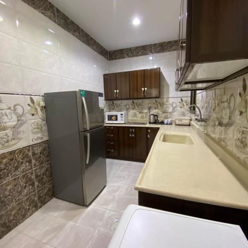 a kitchen with a stainless steel refrigerator and cabinets at بانوراما لشقق المخدومة in Dammam
