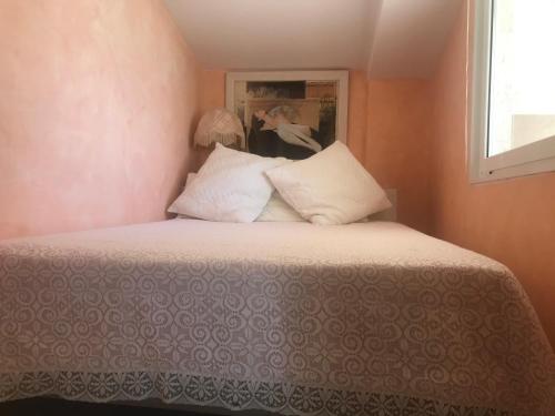 - un lit avec des oreillers blancs et une photo sur le mur dans l'établissement Appartement ensoleillé belle vue dégagée, à Menton