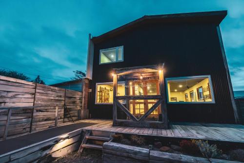 a black house with a wooden door on a deck at Pristine Patagonia Hotel in Puerto Natales