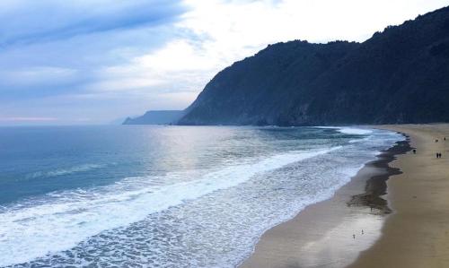 a beach with people walking on the sand and the ocean at Departamento impecable en santa Augusta, Quintay - 6 personas in Quintay