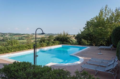 a swimming pool with chairs and a table at Casa Rovelli in Alfiano Natta