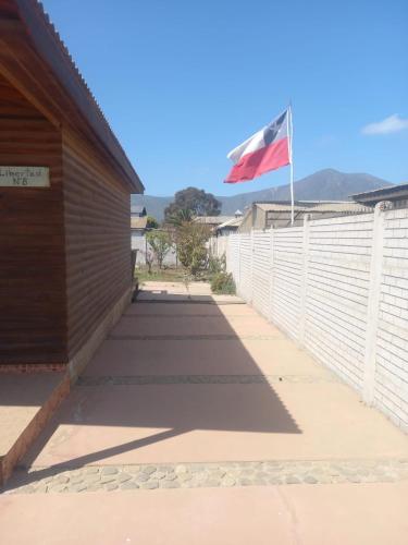 a flag flying over a fence next to a building at Hogareña Cabaña en Quilimari in Quilimarí