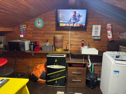 Habitación con TV en la pared y cocina. en Ático com Ar Condicionado Q e F, en Ponta Grossa