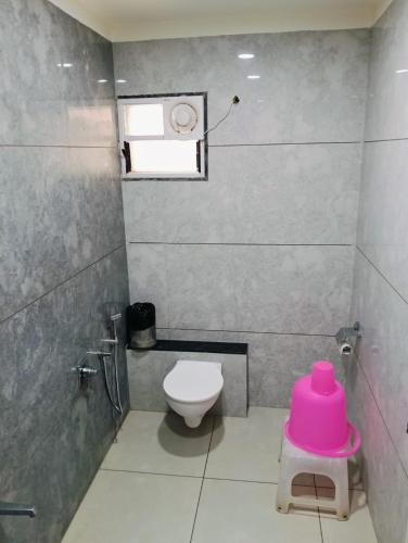 a bathroom with a toilet and a pink stool at Sai Unity Boutique Stay in Garudeshwar