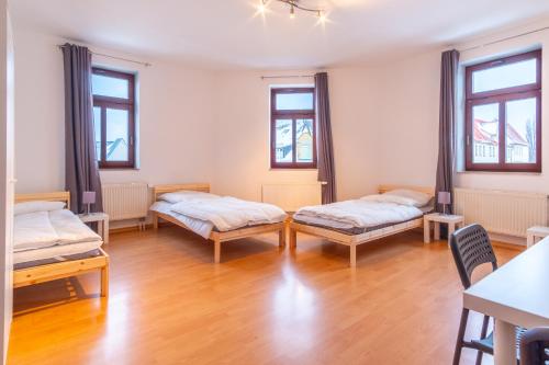 two beds in a room with wooden floors and windows at Perfekt für Gruppen mit Waschmaschine, Einzelbetten, Küche in Chemnitz