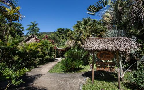 a path through a resort with a sign and palm trees at Omega Tours Eco-Jungle Lodge in La Ceiba
