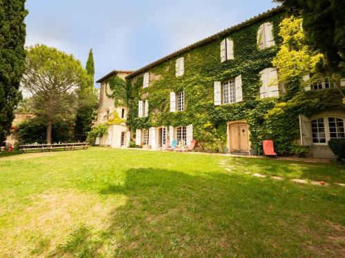 un bâtiment couvert de lierre vert avec une cour herbeuse dans l'établissement Bastide 500m2 Bastide - Piscine, Vue Pyrénées à 180, à Latour