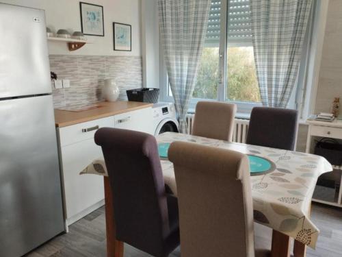 une cuisine avec une table avec des chaises et un réfrigérateur dans l'établissement apartement avec jardin, à Concarneau