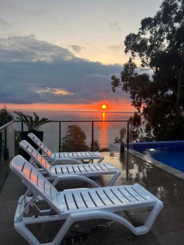 a row of lounge chairs with a sunset in the background at Villa Deluxe Kvariati in Kvariati