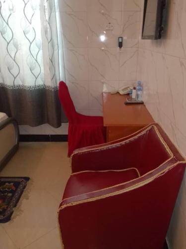 Una silla roja y un escritorio en una habitación. en HP CLASSIC LODGE Manzese, en Dar es Salaam