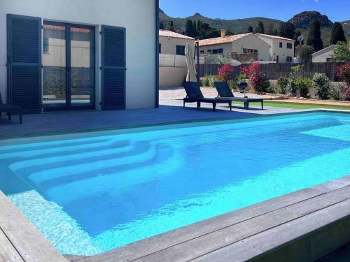 une piscine avec deux chaises à côté d'une maison dans l'établissement Belle villa Amanduli avec piscine, à Calenzana