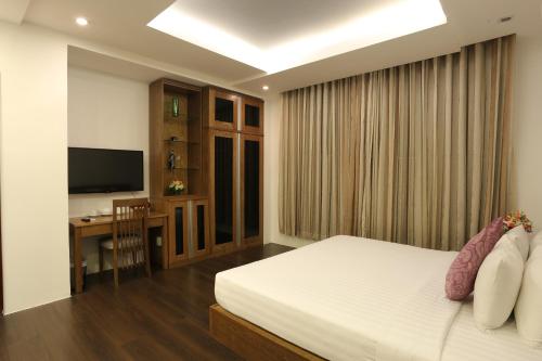 a bedroom with a bed and a desk and a television at Valentine Hotel in Ho Chi Minh City