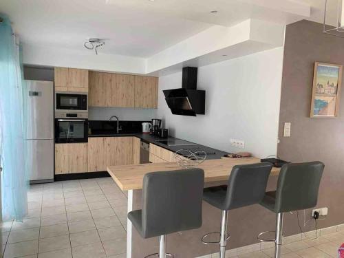 a kitchen with a wooden table and four chairs at Jolie maison cosy proche plage & cité de la voile in Larmor-Plage
