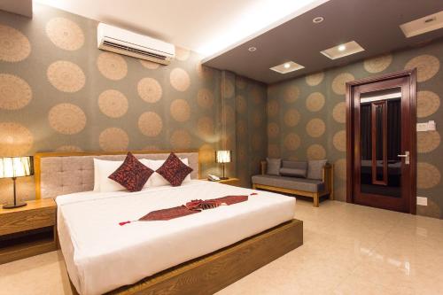 a bedroom with a large white bed and a chair at Valentine Hotel in Ho Chi Minh City