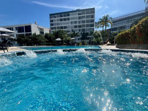 a swimming pool with a water fountain in a city at SUITE INTI vista al mar in Acapulco