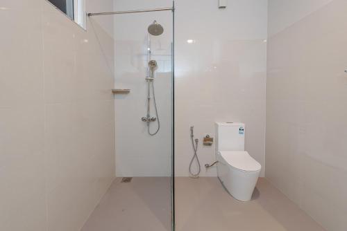 a white bathroom with a shower and a toilet at Ivory Resort Dikwella in Dickwella