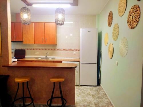 a kitchen with a refrigerator and two bar stools at Casa Rural La Bonica in Molinicos