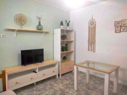 Una sala de estar con un televisor y una mesa. en Casa Rural La Bonica, en Molinicos