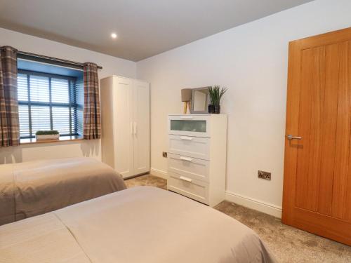 a bedroom with two beds and a dresser and a window at The Steading in Dumfries