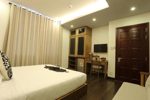 a bedroom with a bed and a desk and a television at Valentine Hotel in Ho Chi Minh City