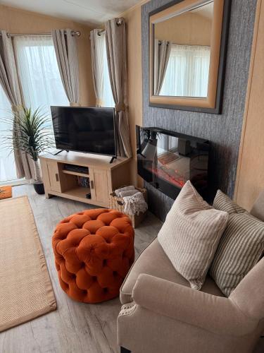 a living room with a couch and a mirror at Stylish Inviting 2 Bedroom Caravan with Sea View in East Mersea