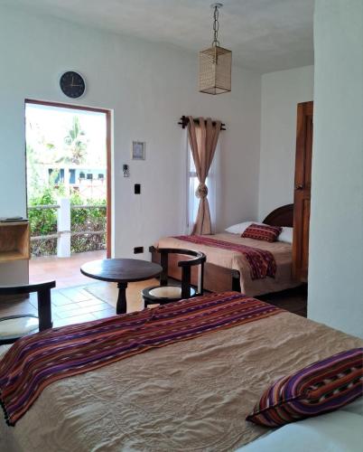 a bedroom with two beds and a table and a window at Hotel Atelie del Mar in Monterrico