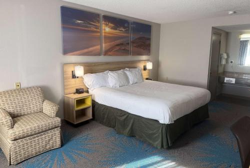 a hotel room with a bed and a chair at Days Inn by Wyndham Hannibal in Hannibal