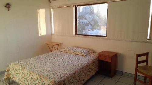 a small bedroom with a bed and a window at Hostal SAKAR Reñaca Beach in Viña del Mar