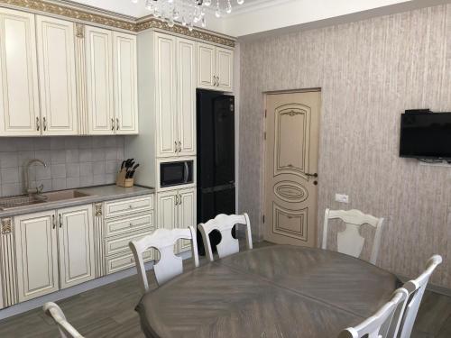 a kitchen with a wooden table and white cabinets at Family home AYT in Yerevan