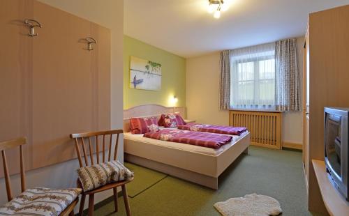 a bedroom with a bed and a chair and a tv at Bio Angererhof in Bad Häring