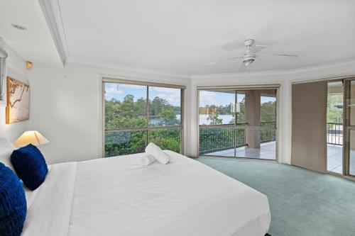 a white bedroom with a large white bed and windows at Front Lake View 4Bed Home with Pool and Mins to Mall in Doolandella