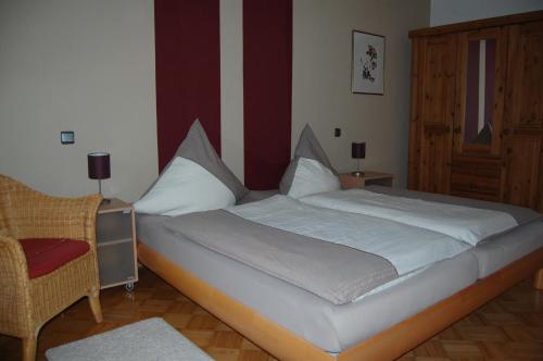 1 dormitorio con 1 cama blanca grande y 1 silla en Ferienhaus Ginsterblüte, en Schleiden