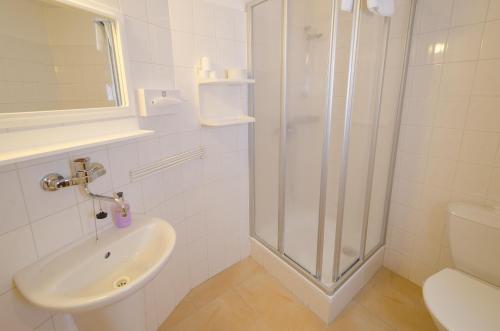 a white bathroom with a shower and a sink at Penzion Globus in Český Krumlov