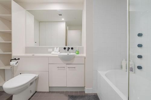 a white bathroom with a sink and a toilet and a tub at Best Value 2Beds Apt at CBD with Pool Gym Carpark in Brisbane