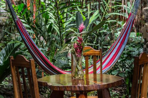 a vase on a table with a hammock at Omega Tours Eco-Jungle Lodge in La Ceiba