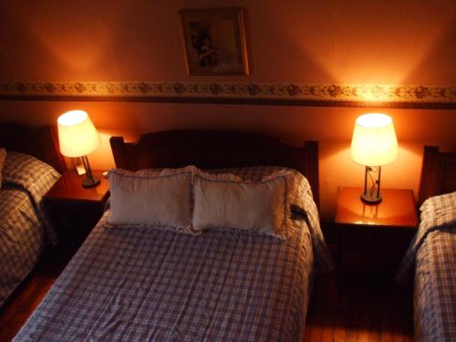 a bedroom with two twin beds and two lamps at Hotel Posada del Angel in Cuenca