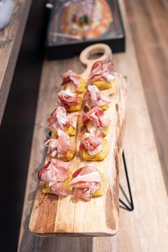 a wooden cutting board with ham on top of it at Riserva Bianca Limone Hotel & SPA in Limone Piemonte