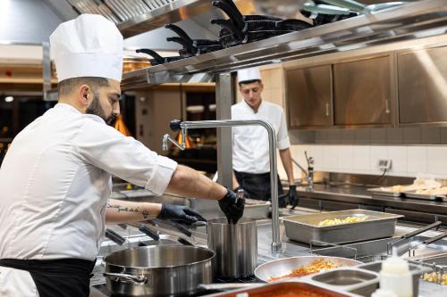 two chefs are preparing food in a kitchen at Riserva Bianca Limone Hotel & SPA in Limone Piemonte