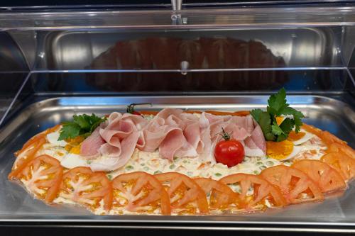 a pizza with ham on top of it in an oven at Riserva Bianca Limone Hotel & SPA in Limone Piemonte