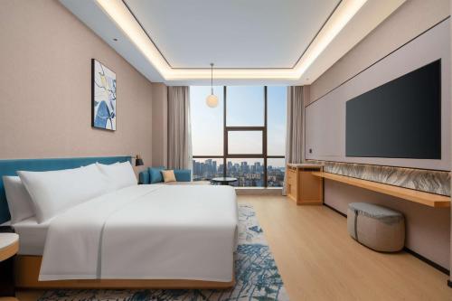 a hotel room with a bed and a flat screen tv at Hilton Garden Inn Xuzhou Pengcheng Square in Xuzhou