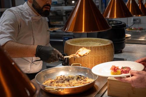 a man is preparing food in a kitchen at Riserva Bianca Limone Hotel & SPA in Limone Piemonte