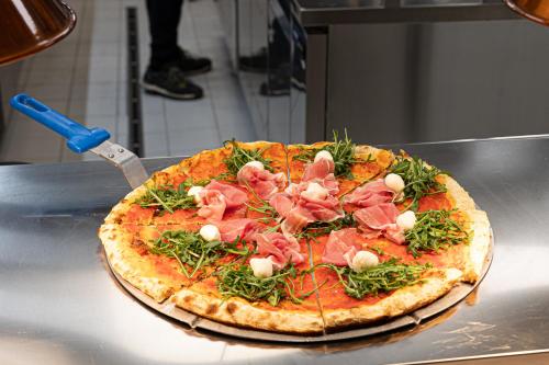 a pizza with ham and vegetables on a table at Riserva Bianca Limone Hotel & SPA in Limone Piemonte