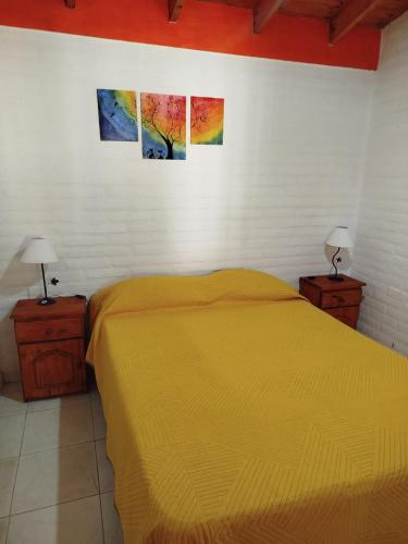 a bedroom with a yellow bed and two pictures on the wall at Cabañas del Puente - Rio Grande San Luis in La Bajada