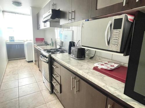 a kitchen with a stove and a microwave at Departamento 2D en Iquique!!! in Iquique