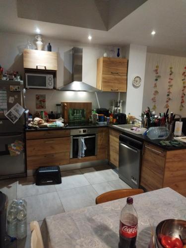 - une cuisine avec des placards en bois et une table avec une bouteille de soda dans l'établissement chambre 3lits chez l'habitant, à Dunkerque