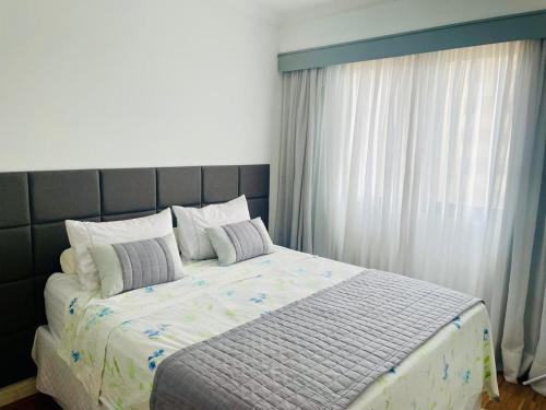 a bedroom with a large bed with a large window at The Palace Flat Moema in Sao Paulo